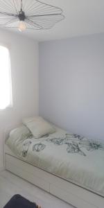 a bed in a white bedroom with a ceiling at Appt entier Résidence de la Plage Vue Mer Port Navalo in Arzon