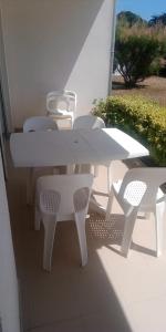 uma mesa branca e cadeiras sentadas num pátio em Appt entier Résidence de la Plage Vue Mer Port Navalo em Arzon
