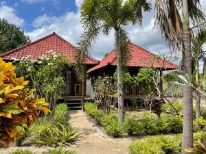 dom z czerwonym dachem i palmami w obiekcie Mangrove Beach Hut w mieście Nusa Lembongan