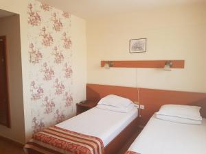 two beds in a room with flowers on the wall at Hotel Transit in Oradea