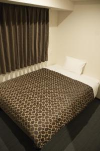 a bedroom with a bed with a brown blanket at Hotel Excellence Kyoto Ekimae in Kyoto