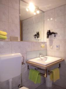 ein Badezimmer mit einem Waschbecken, einem Spiegel und einem WC in der Unterkunft Ferienwohnungen Anna Balazs in Illmitz