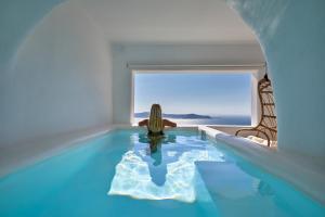 a woman sitting in a pool with a view of the ocean at U & ME SUITES in Fira