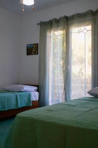 1 dormitorio con 2 camas y ventana en Ευχάριστη Βίλα, 90 μέτρα από τη θάλασσα, en Agioi Theodoroi