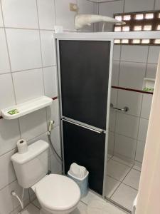 a bathroom with a toilet and a black door at Pousada Lá Na Praia in São José da Coroa Grande