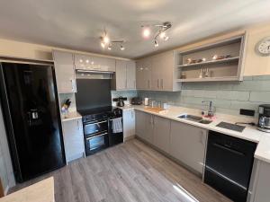 a kitchen with white cabinets and black appliances at The Emberton in Bridlington