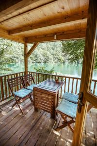 a wooden deck with a table and chairs and a lake at Riverland in Gornji Zvečaj