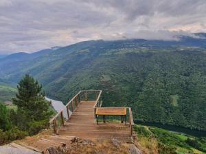 une promenade en bois avec un banc au sommet d'une montagne dans l'établissement Casa do Hiebra Alojamiento Rural Ribeira Sacra, à Castroncelos