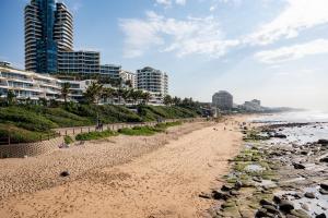 a beach with buildings and people walking on it at Oceans Umhlanga Accommodation in Durban