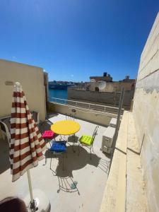 a patio with a table and chairs and an umbrella at MoCo, modern comfort in historic city of Senglea in Senglea