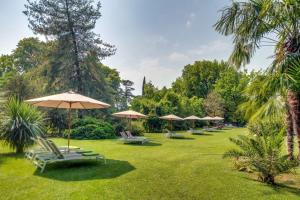 a row of umbrellas and lounge chairs in a park at Rambaldi Apartments Casa nr 2 in Bardolino