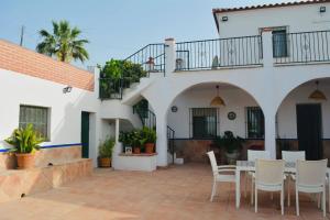 Un patio con una mesa y sillas frente a un edificio. en Casa Con Piscina Y Pista De Tenis, en Alhaurín de la Torre