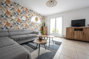 een woonkamer met een bank en een tv bij Maison pour 6 entre Marais salants et plages in Les Bussolleries