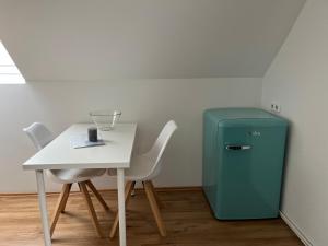 uma mesa e um frigorífico verde ao lado de uma mesa e cadeiras em Deich Winde 9.1 em Dorum Neufeld