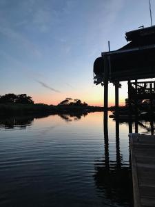 a view of a lake with a dock and the sunset at Cottage by the Sea: Pagnotto Shellback House in Oak Island