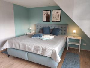 een slaapkamer met een bed met blauwe muren en 2 tafels bij Ferienhaus Blaue Blume mit 11 kW Ladestation, Kamin, Terrasse, eingezäuntem Garten, Sauna, WLAN, Netflix, 2 Hunde willkommen! in Güntersberge