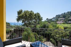 a balcony with a view of the ocean and trees at Hôtel de La Fossette in Le Lavandou