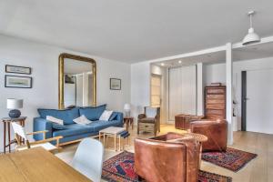ein Wohnzimmer mit einem blauen Sofa und einem Spiegel in der Unterkunft Superb flat with terrace nearby the Eiffel Tower - Welkeys in Paris
