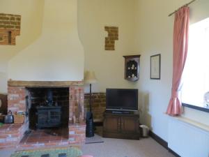 a living room with a fireplace and a television at The Smithy in Snettisham