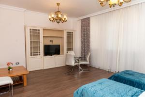 een slaapkamer met een bed en een televisie en een tafel bij Utopia Hotel Baku in Baku