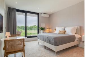 a bedroom with a bed and a large window at Hello Zeeland - Summum Suites in Domburg