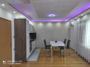 uma cozinha e sala de jantar com uma mesa e luzes roxas em Home of nature - kuća prirode em Odžak