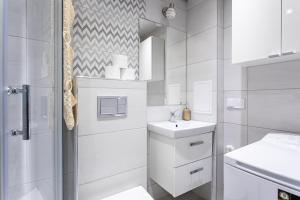 a white bathroom with a sink and a shower at 3Bedrooms Comfy Flat Celarowska in Kraków