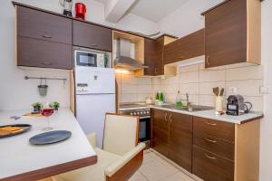 eine Küche mit Holzschränken und einem weißen Kühlschrank in der Unterkunft cozy panta in Orestiada