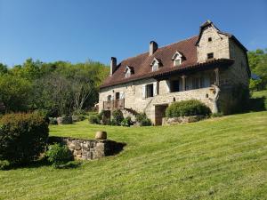 ein altes Steinhaus auf einem grünen Feld in der Unterkunft Villa La Cayrouse Piscine Tennis Boulodrome in Le Bouyssou