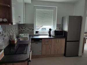 a kitchen with a stainless steel refrigerator and a sink at Dévai-LUX Apartman Sárvár in Sárvár