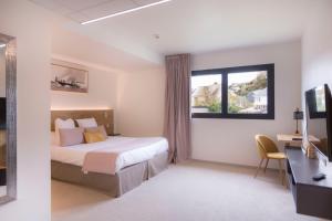 1 dormitorio con cama, escritorio y ventana en Le Nautica Hôtel, en Perros-Guirec