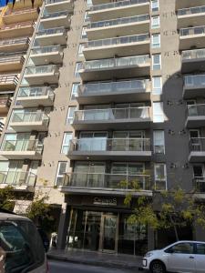 een appartementengebouw met ervoor geparkeerde auto's bij Alucinante departamento en La Perla 3 ambientes con aire acondicionado y calefacción central in Mar del Plata