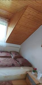 a bed in a room with a wooden ceiling at Kéktúrás-Tóra Nyíló privát bérlemény in Badacsonytomaj