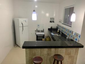 a kitchen with a refrigerator and two bar stools at Aloha Beach Temporada in Cabo Frio