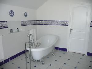 La salle de bains est pourvue d'une baignoire blanche et de carrelage bleu et blanc. dans l'établissement Chateau des Barrigards, à Ladoix Serrigny