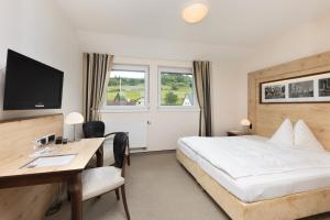 a hotel room with a bed and a desk at Hotel im Auerbachtal in Bad Laasphe