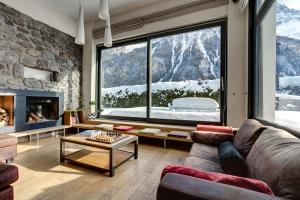 ein Wohnzimmer mit Couch und großem Fenster in der Unterkunft Chalet Safari. Face au Mont-Blanc. in Chamonix-Mont-Blanc