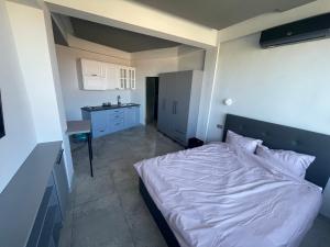 a bedroom with a white bed and a kitchen at Engels apartment in Cluj-Napoca