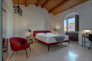 a bedroom with a bed and a red chair at PIANELLE RESORT in Matera