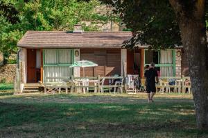 Village Gévaudan Aubrac في مارفيجول: رجل يمر بجانب منزل به طاولة وكراسي