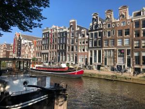 dwie łodzie zacumowane w kanale z budynkami w obiekcie Canal Hideaway w Amsterdamie