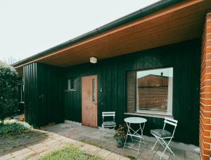 a green house with two chairs and a table at Pieni lomahuoneisto ja ulkoporeallas in Mynämäki