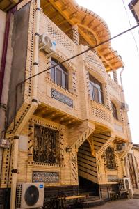 a wooden building with a balcony on a street at Durdona Guest House in Samarkand