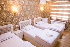Pokój z 3 łóżkami i ścianą w obiekcie Durdona Guest House w Samarkandzie