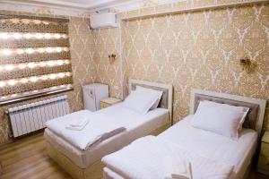 Pokój z 2 łóżkami i ścianą w obiekcie Durdona Guest House w Samarkandzie
