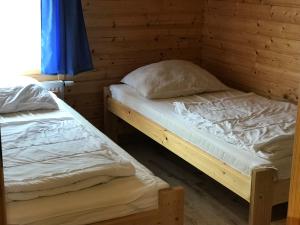 two twin beds in a room with wooden walls at Domki Prestige in Ustronie Morskie