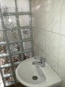 Malomtavi Vendégház في تابولتسا: حمام مع حوض أبيض وجدار زجاجي
