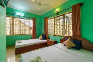 2 camas en una habitación con paredes y ventanas verdes en Happy Heng Heang Guesthouse, en Siem Reap