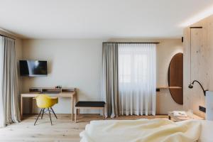 a bedroom with a bed and a desk with a yellow chair at Hotel Alpenrose in Au im Bregenzerwald