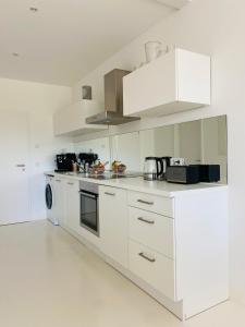 una cocina blanca con armarios y electrodomésticos blancos en FeWo Silberberg im Loftstil mit Terrasse, en Leonberg